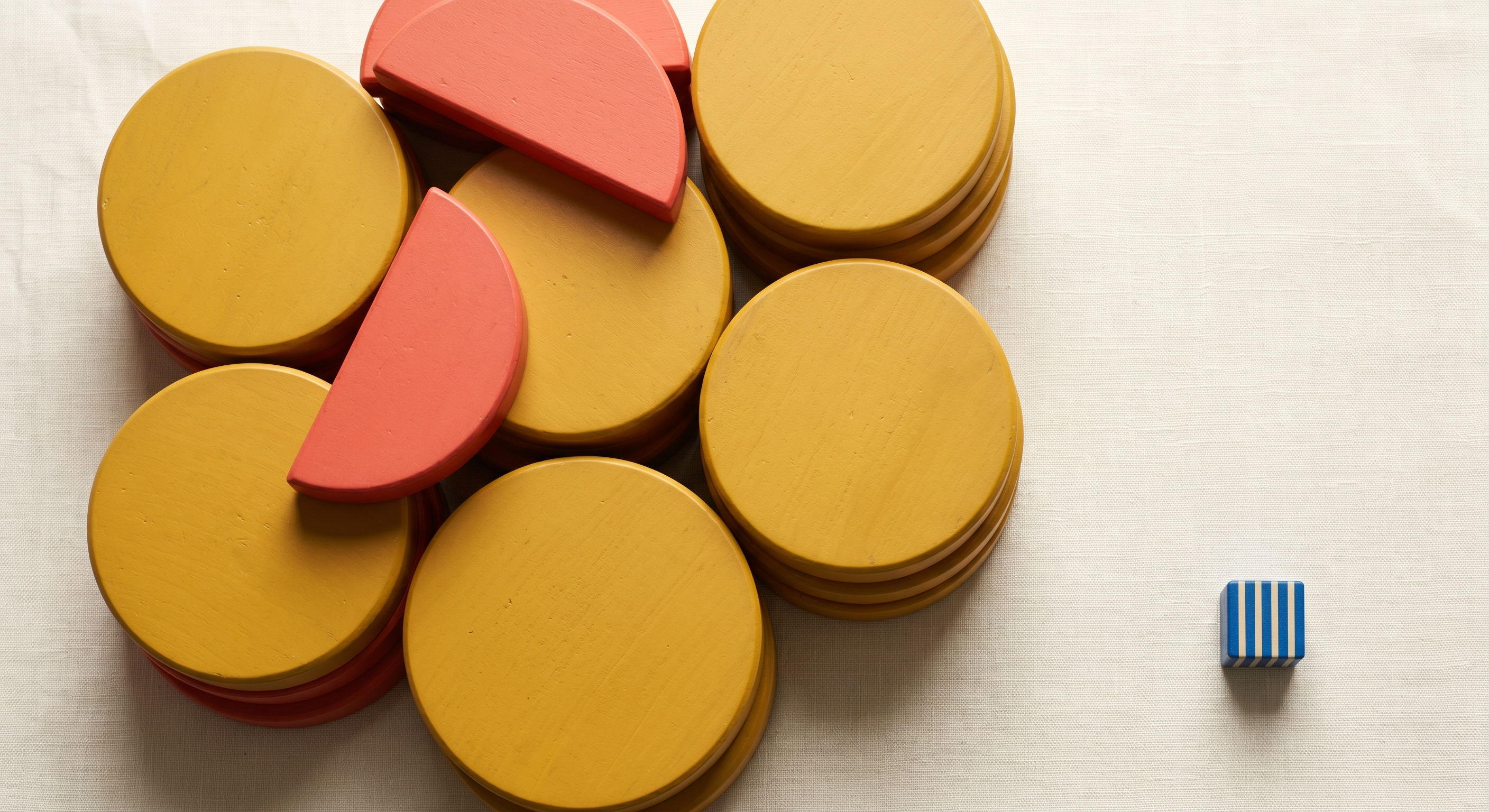 Large golden circles and coral half-moons dominating the frame with a single tiny blue striped square in the corner