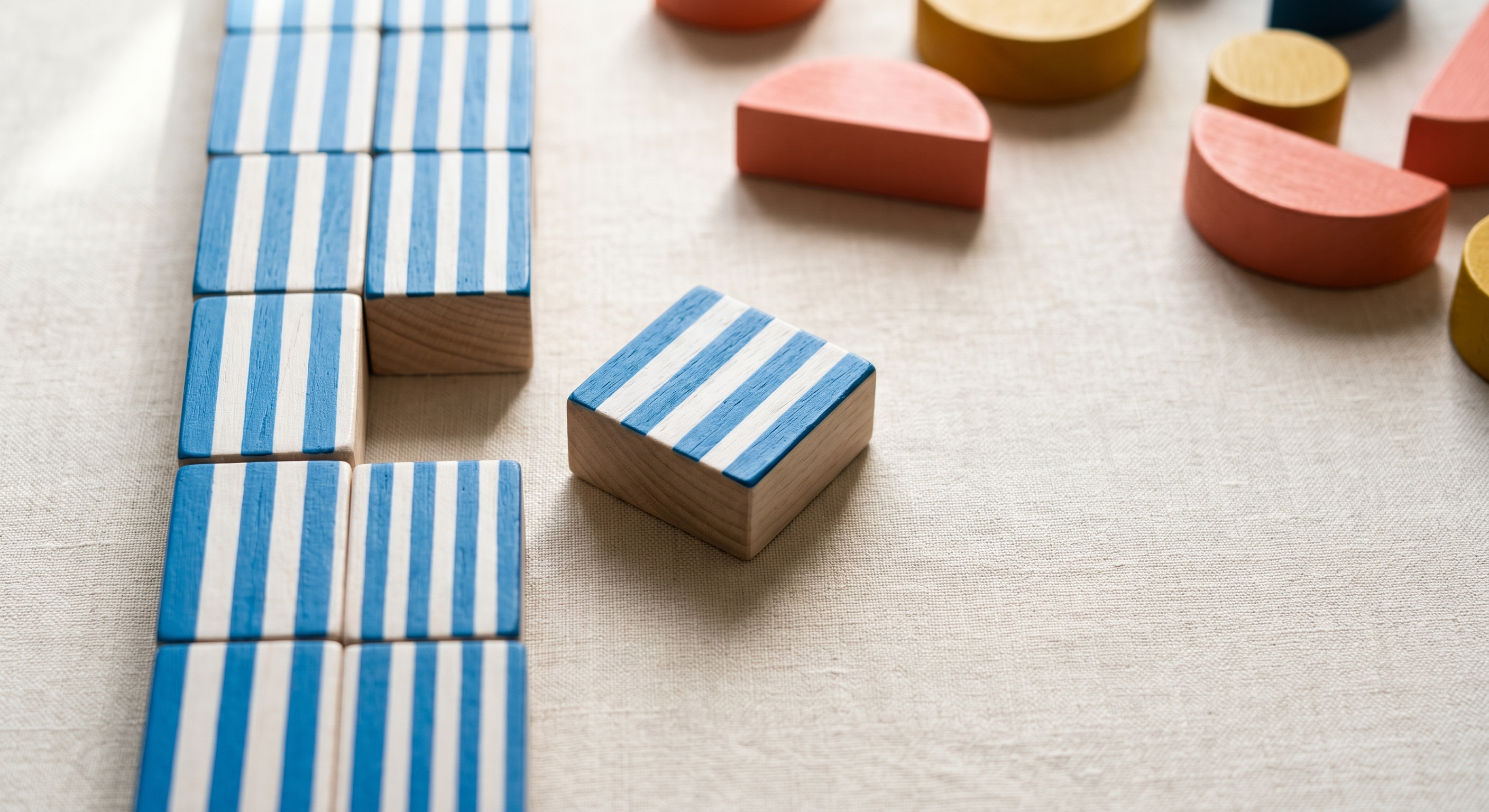 Column of blue striped wooden squares with one pulled out leaving a gap on cream linen