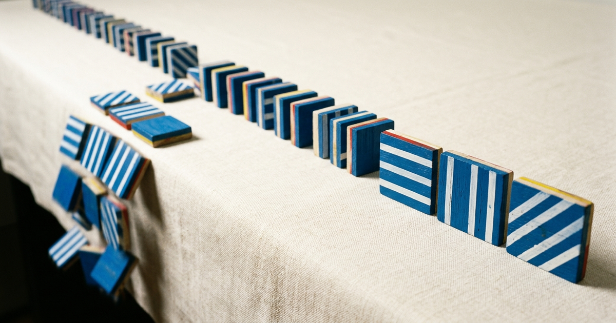 Stack of blue striped envelope shapes tipping into a navy four-petal mark on cream linen