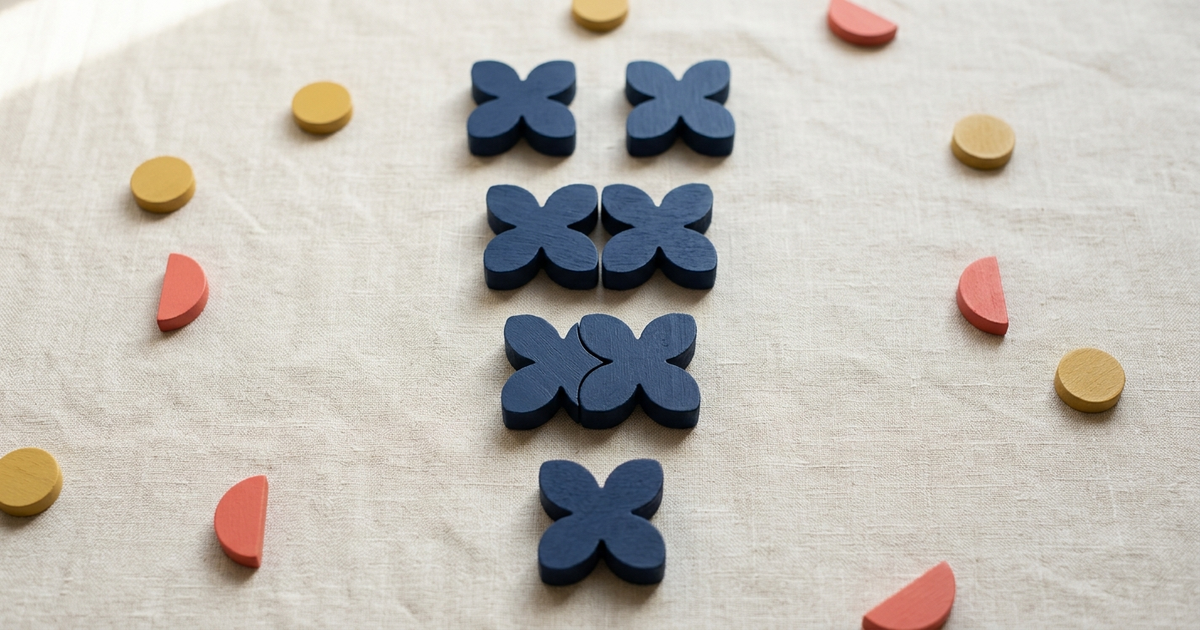 Two overlapping rings of beige and navy pebbles merging into a single ring on cream linen